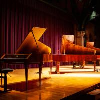 Four historical pianos onstage in Barnes Hall auditorium