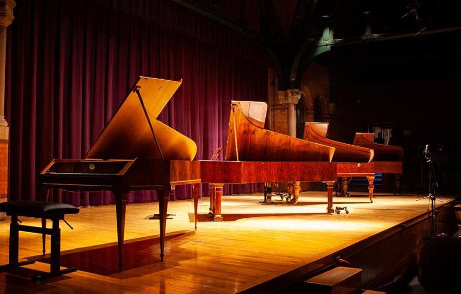 Four historical pianos onstage in Barnes Hall auditorium
