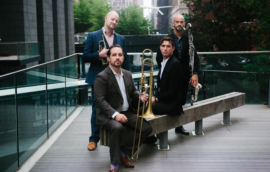 Four men in suits with trumpet, trombone, and bass clarinet