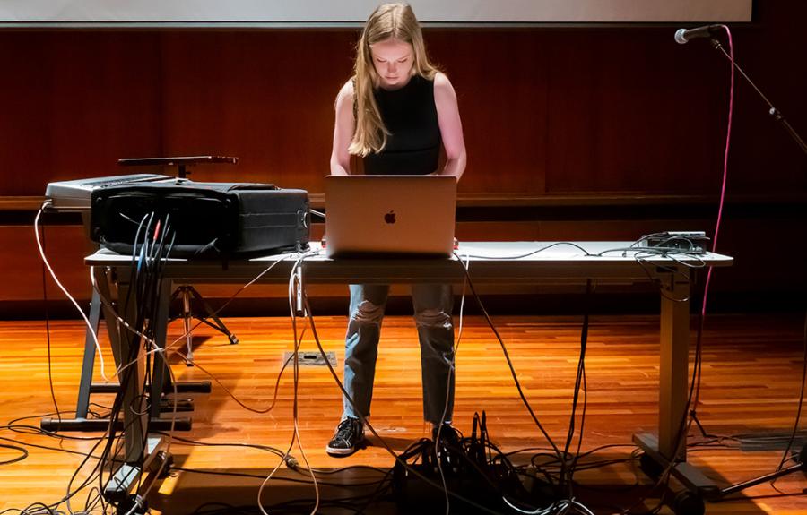 A student performs electronic music at a laptop