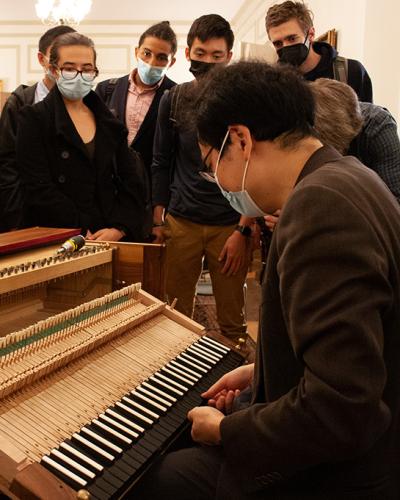 Mike Lee shows the inner workings of a keyboard instrument while students look on