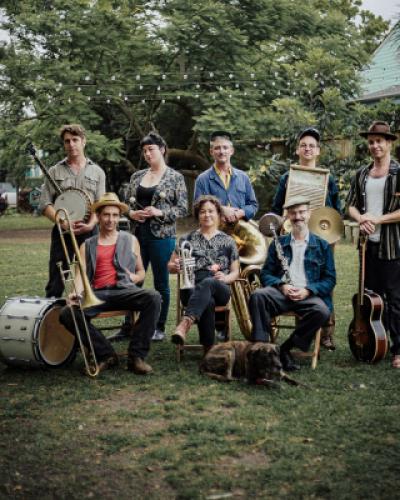 Variety of musicians with New Orleans brass band instruments in a yard